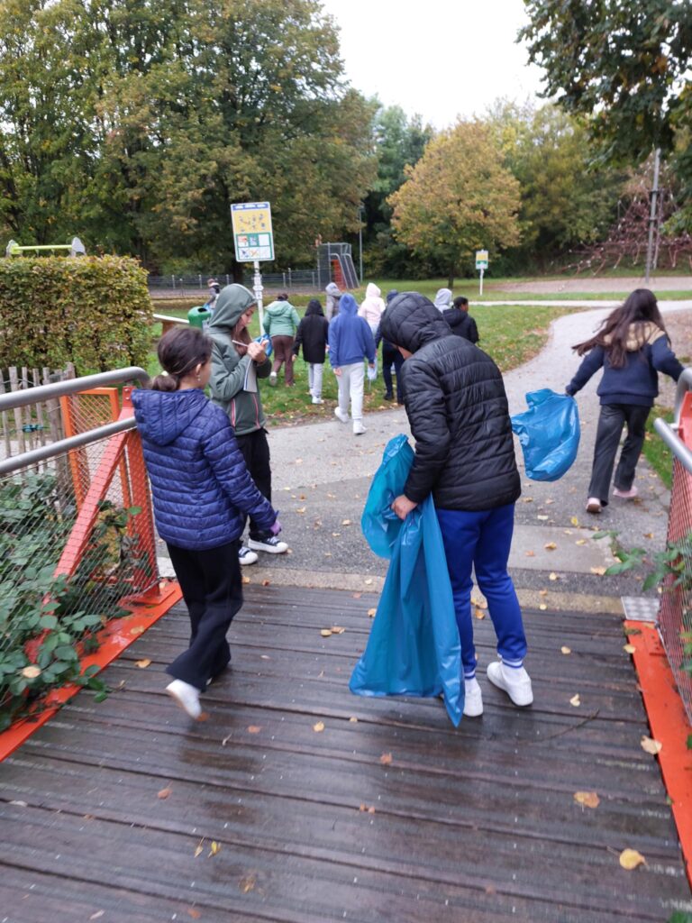 élèves dans le parc à Pétange, équipés de sac bleus , en train de ramasser des déchets
