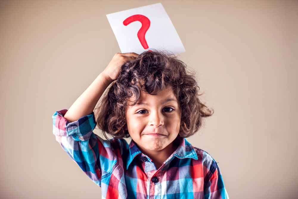 Ein Kind mit einem Fragezeichen über dem Kopf. Es stellt sich Fragen.